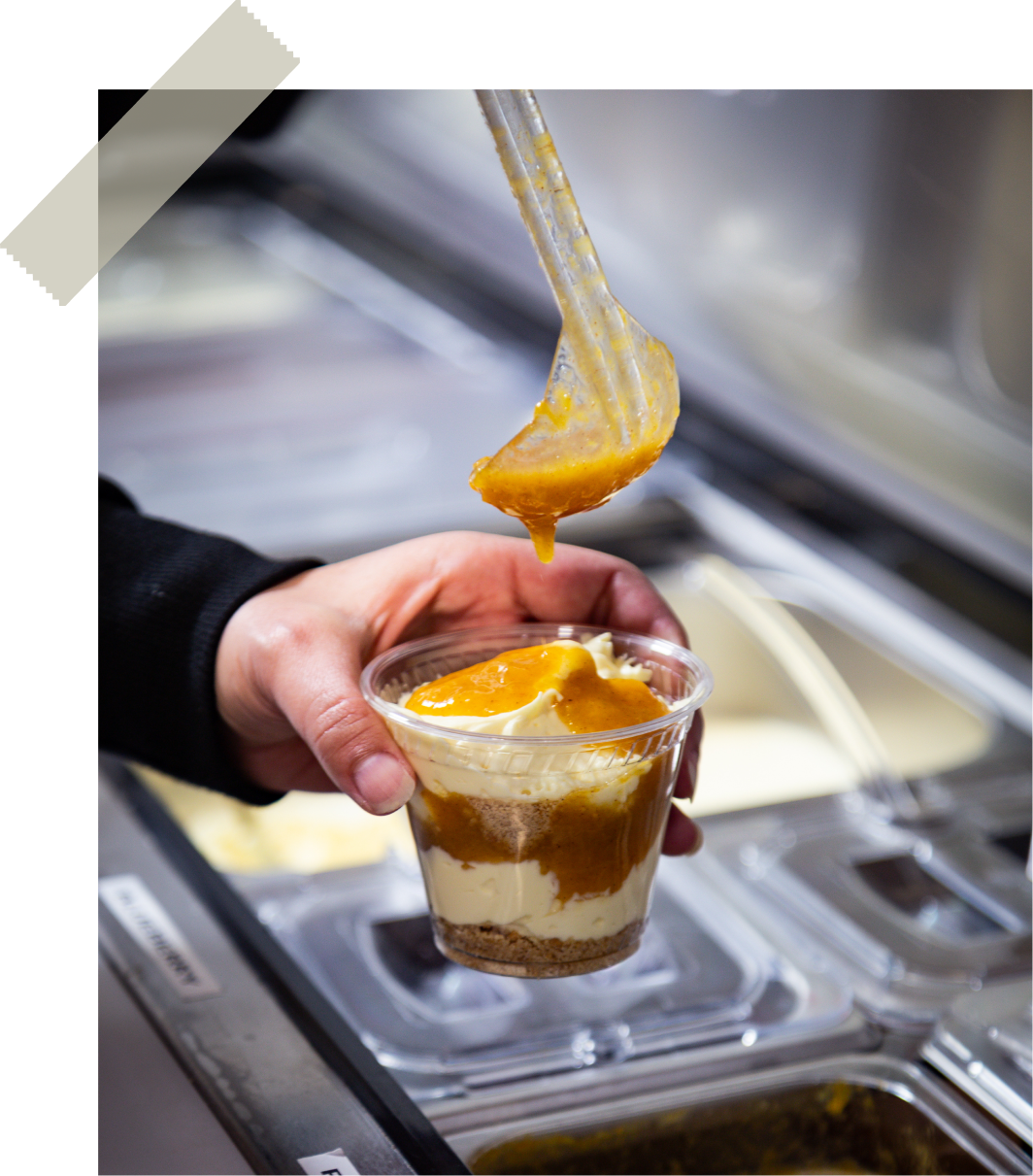 Warm caramel peach sauce being spooned over a fresh parfait cup